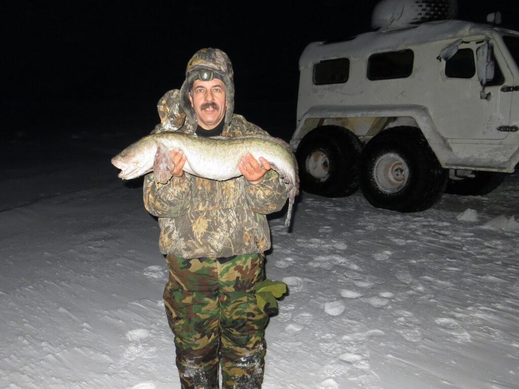 Ice fisherman at night with a catch